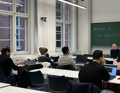 Seminarraum, in dem Studierende von hinten zu sehen sind