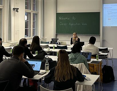 Seminarraum, in dem Studierende von hinten zu sehen sind