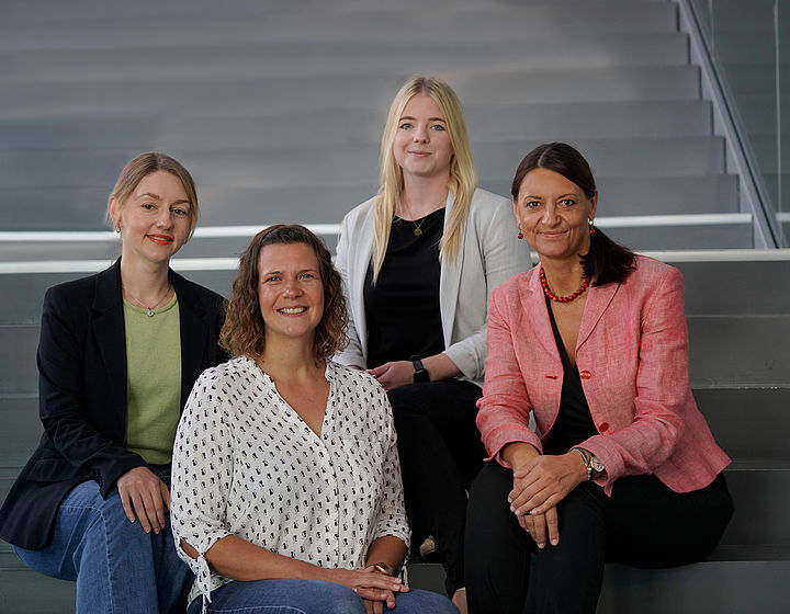 Gruppenbild des Teams vom karrierezentrum für professorale Entwicklung. Die vier Mitarbeiterinnen sitzen auf einer Treppe und lächeln in die Kamera.