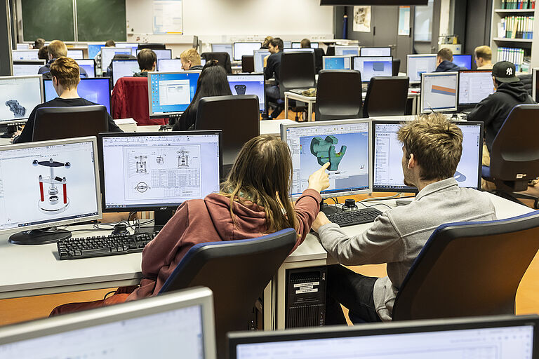 Studierende in einem Seminarraum vor einem PC-Bildschirm