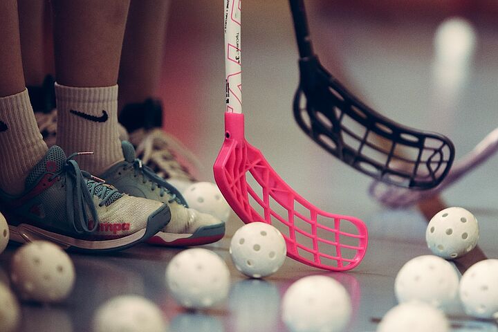 Hockeybälle auf dem Boden mit Schlägern daneben