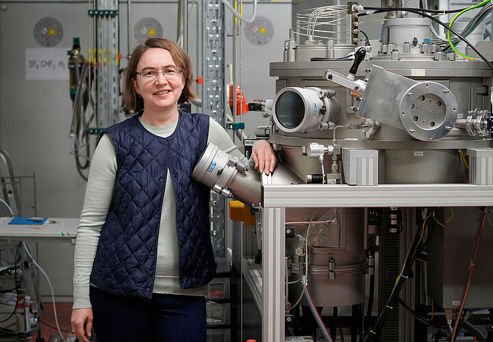 Eine Professorin lehnt an einem Laser in einem Physiklabor.
