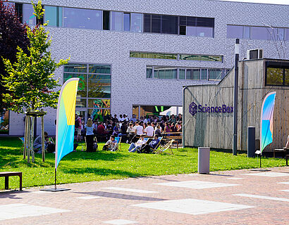 Gebäude der TH Wildau mit Studierende auf der Campuswiese und Beachflags davor