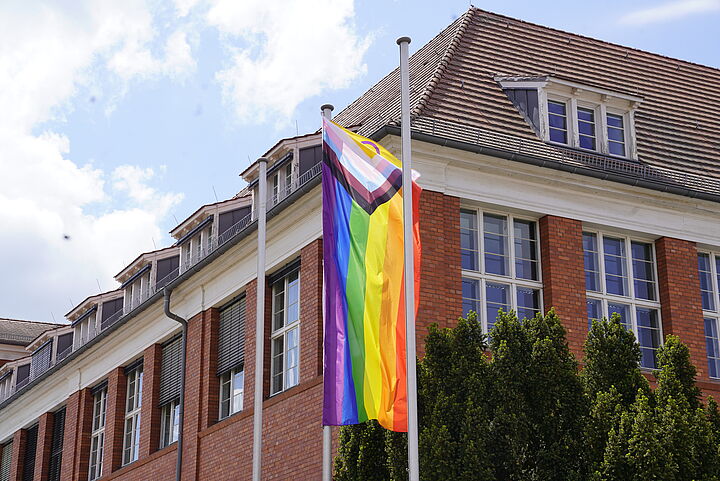 Die Inter-inclusive Pride Flag hängt an einem Fahnenmast vor dem Verwaltungsgebäude der TH Wildau.