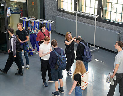 Studierende im Foyer eines Hörsaalgebäudes bekommen ihren Erstsemester-Löffel umgehängt