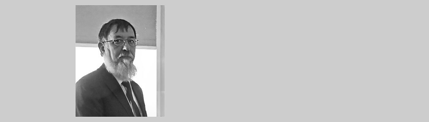 Collage aus grauem Hintergrund und Portraitbild eines älteren Mannes mit langem weißen Bart und Brille