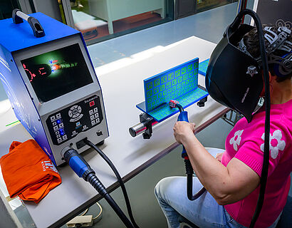 Besucherin des HIT 2024 mit einer VR-Brille auf dem Kopf in Halle 14 auf dem Campus.