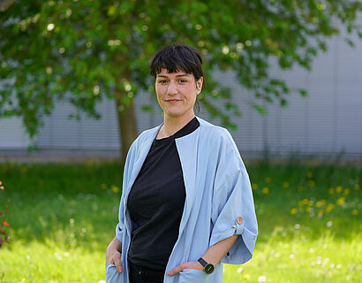 Mitarbeiterin Constanze Eichler steht auf einer grünen Wiese auf dem Campus der TH Wildau