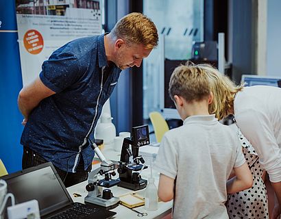 Bild Hochschulinformationtag Junge betrachtet Mikroskop