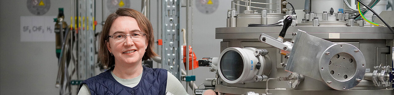 Porträt einer lächelnden Professorin in einem Physiklabor neben einem Laser.