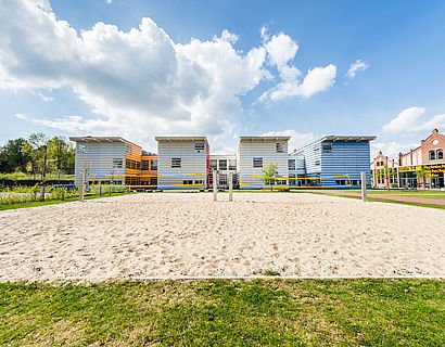 Blick auf das Beachvolleyballfeld und Haus 15